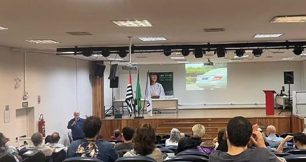 Palestra para plateia em auditório, com apresentação projetada na tela